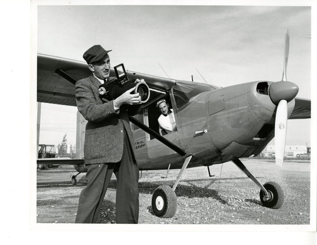 George Hunter with camera in front of plane